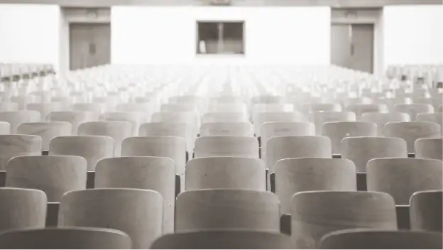 Interior of traditional college auditorium classroom with rows of empty wooden chairs